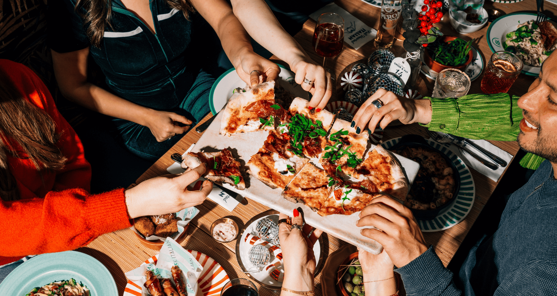 A group of people enjoying a Christmas party at ASK Italian restaurants, with everyone tucking into a festive special pizza.